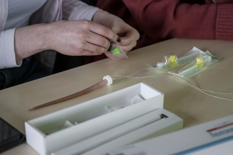 Hände packen Material aus, auf dem Tisch liegt ein künstlicher Rattenschwanz
