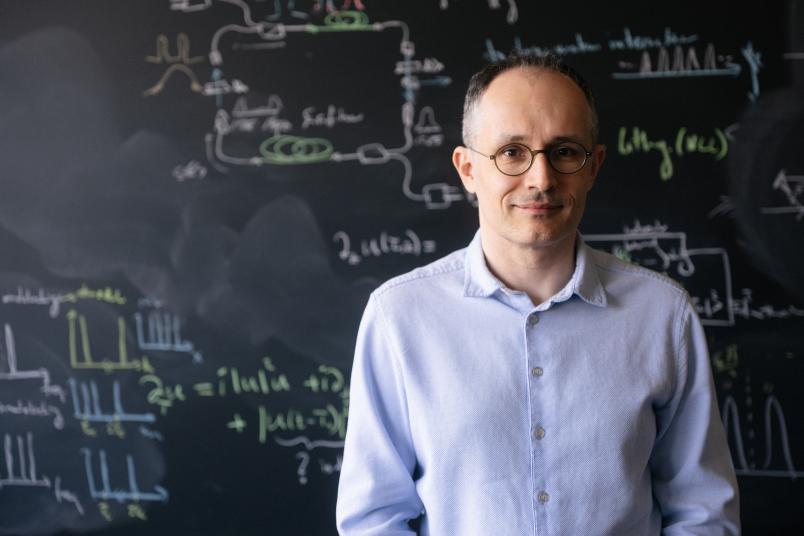 Porträt von Ömer Ilday vor einer Tafel mit mathematischen Gleichungen