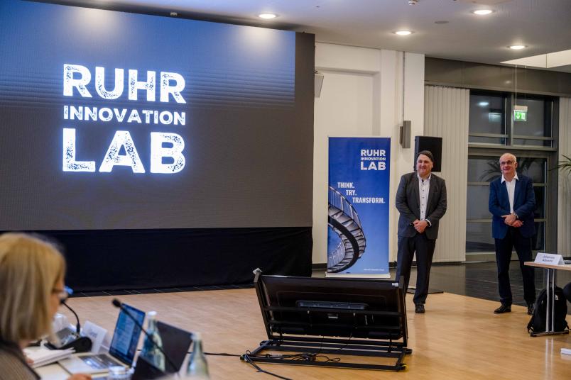 Die Rektoren Martin Paul und Manfred Bayer vir einer LED-Wand mit Ruhr-Innovation-Lab-Logo