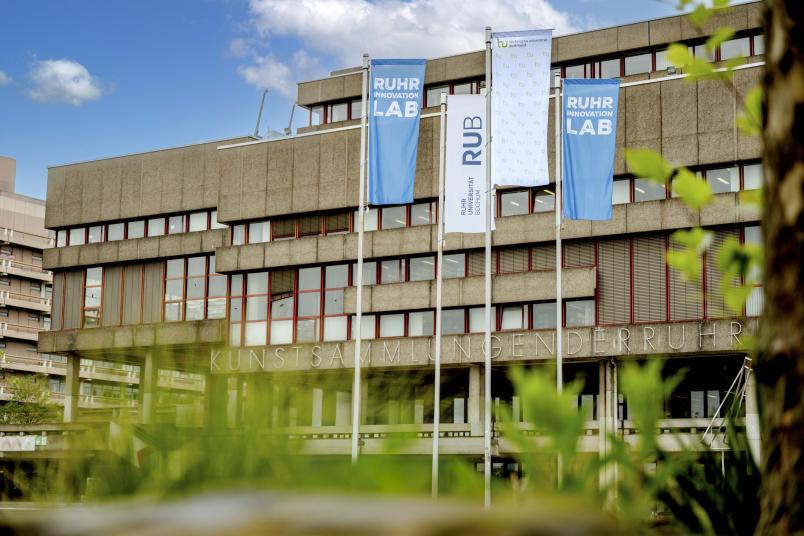 Flaggen von RUB, TU Dortmund und Ruhr Innovation Lab vor der Unibibliothek