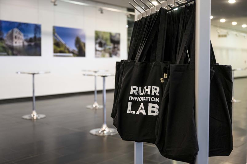 Schwarze Stoffbeutel mit Ruhr-Innovation-Lab-Logo im Foyer des Veranstaltungszentrums