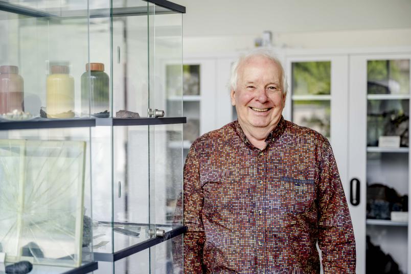 Eine Person steht vor einem Glasregal mit verschiedenen Exponaten