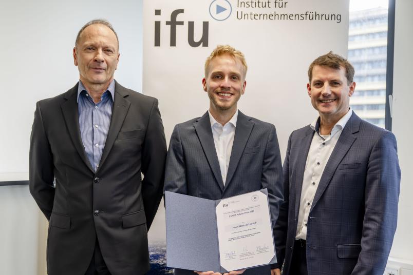 Drei Männer, einer davon mit Urkunde