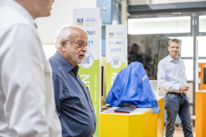 Ein Mann im blauen Hemd zwischen anderen Personen