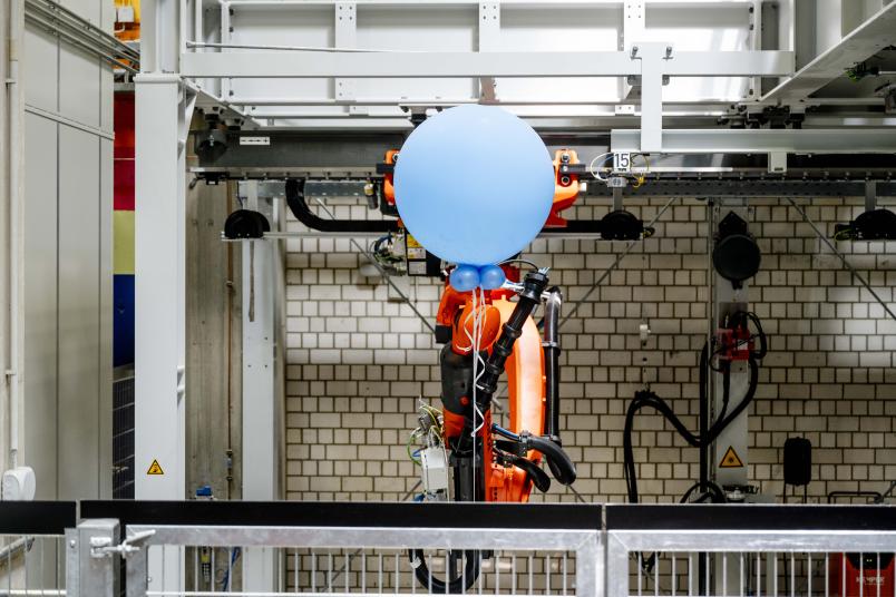 Roboter peilt blauen Ballon mit einem Werkzeug an