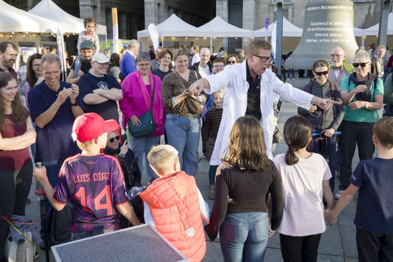 Ein Mann im weißen Kittel inmitten einer Schar Kinder