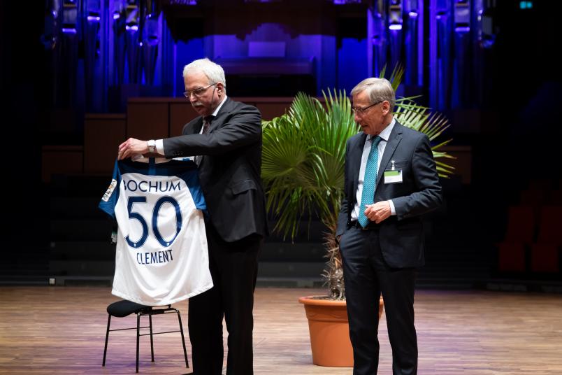 Ein Trikot mit der Rückennummer 50 von seinem Lieblingsverein VfL Bochum hat der ehemalige NRW-Ministerpräsident Wolfgang Clement (rechts) von Medizin-Dekan Ralf Gold überreicht bekommen.