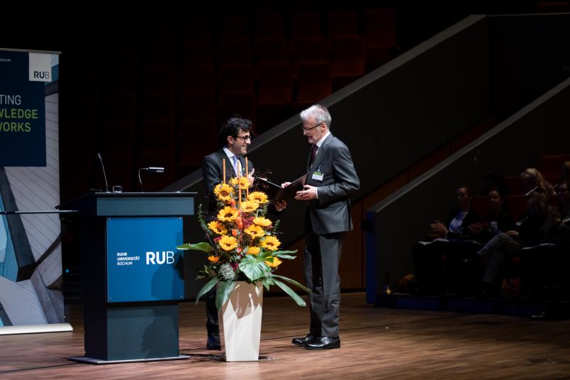 Prof. Dr. Aiden Haghikia (links) überreicht für die Fakultät die Urkunde zur Ehrenpromotion an Prof. Dr. Reinhard Hohlfeld.