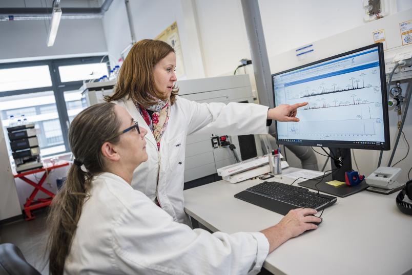 Zwei Personen in weißen Kitteln schauen Daten auf einem Computer an
