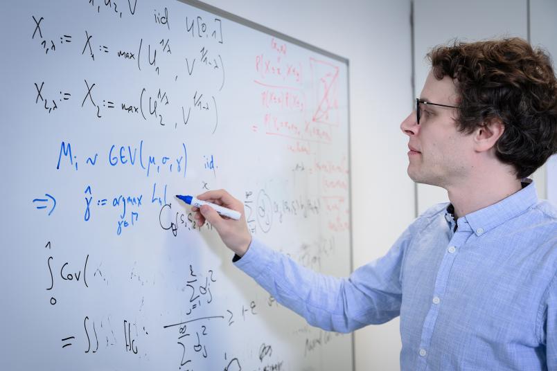 Eine Person schreibt mathematische Formeln an ein Whiteboard.