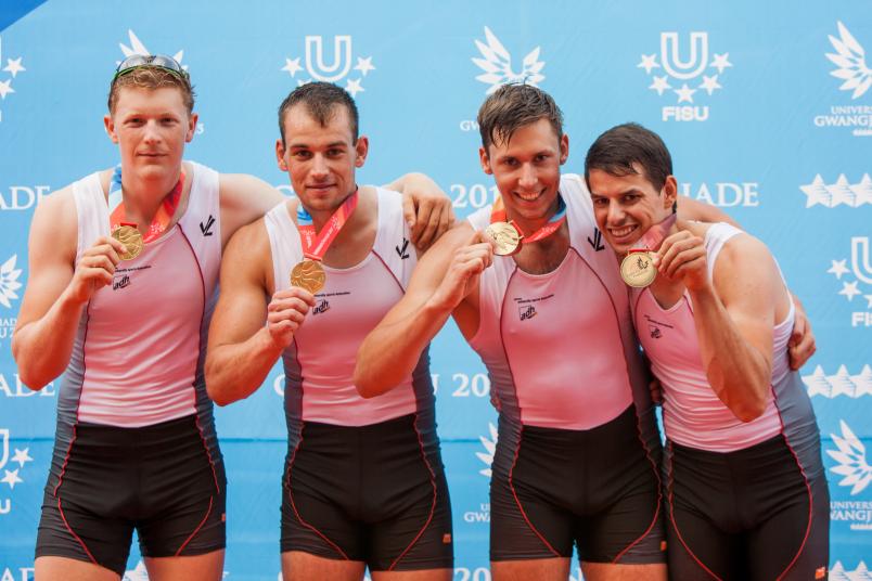Vier Athleten stehen mit ihren Goldmedaillen fröhlich nebeneinander