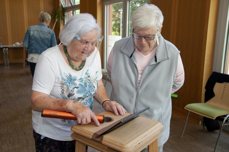 zwei ältere frauen probieren ein Tool aus