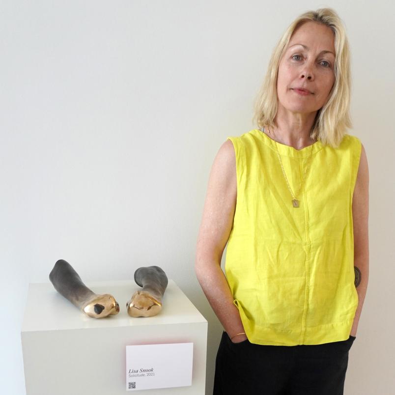 Eine Person neben einer Skulptur von zwei geballten Fäusten