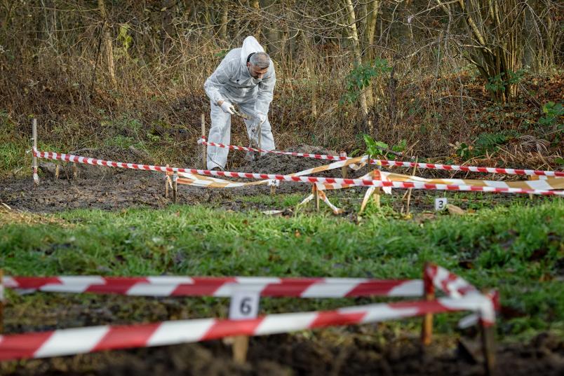 Person vergräbt etwas in einem eingezäunten Gelände