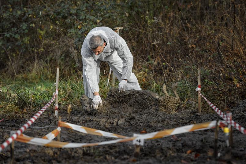 Person vergräbt etwas in einem eingezäunten Gelände