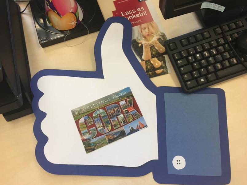 Ein Like-Daumen, auf dem eine Ansichtskarte liegt.