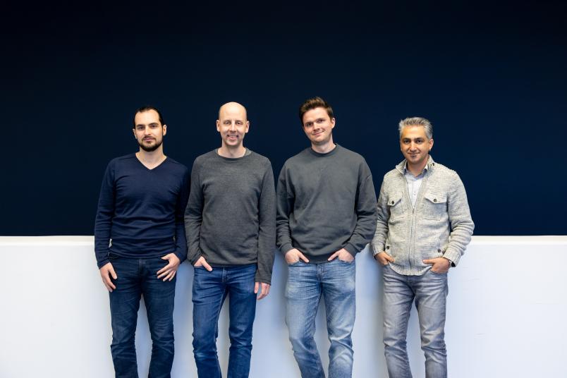 Vier Personen vor einer blau-weißen Wand