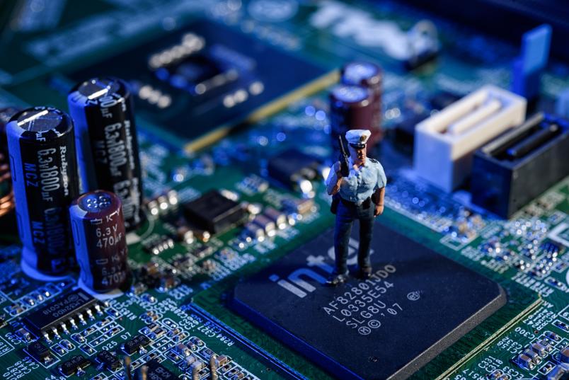 Blick auf einen Computerchip, auf dem ein Polizisten-Modellmännchen steht. 