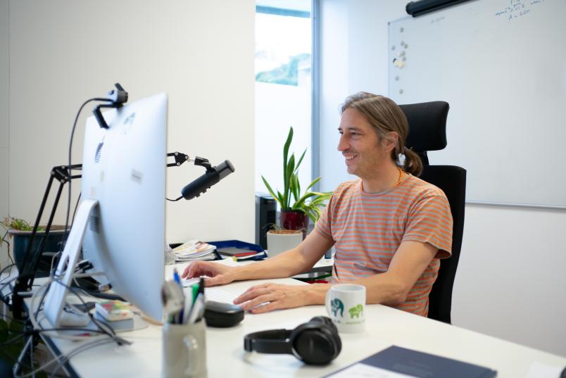 Eine Person an einem Schreibtisch arbeitet an einem Computer.