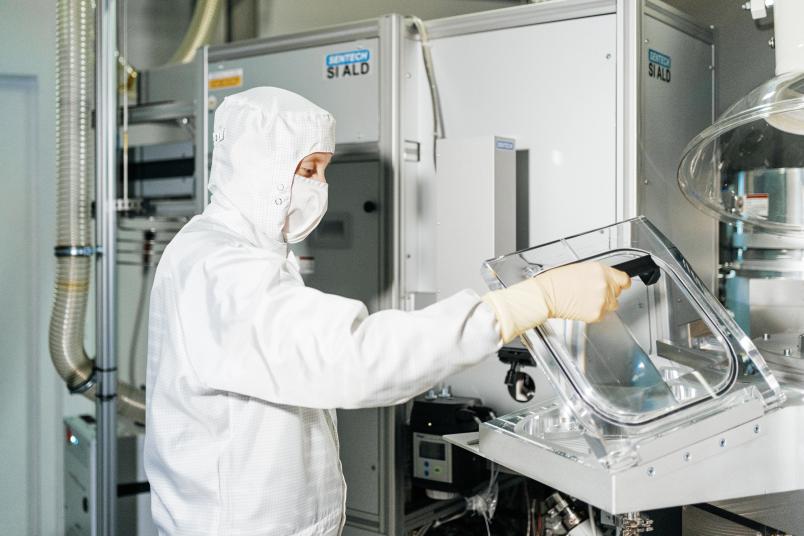 Eine Person in weßer Schutzkleidung bedient eine technische Anlage.