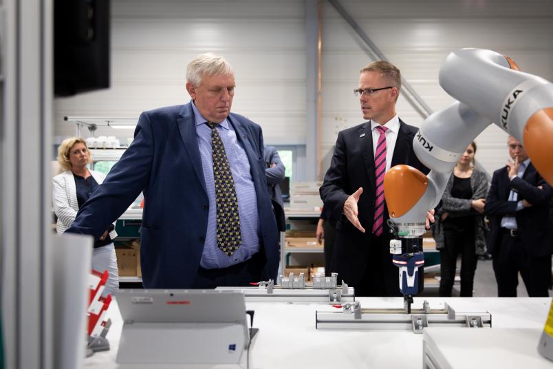 NRW-Arbeitsminister Karl-Josef Laumann (links) besucht die Bochumer Lern- und Forschungsfabrik. Was der Roboterarm macht, erläutert Bernd Kuhlenkötter.