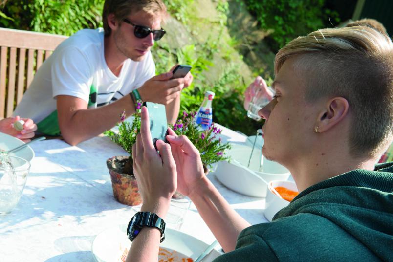 Junge Leute beim Essen mit Handy