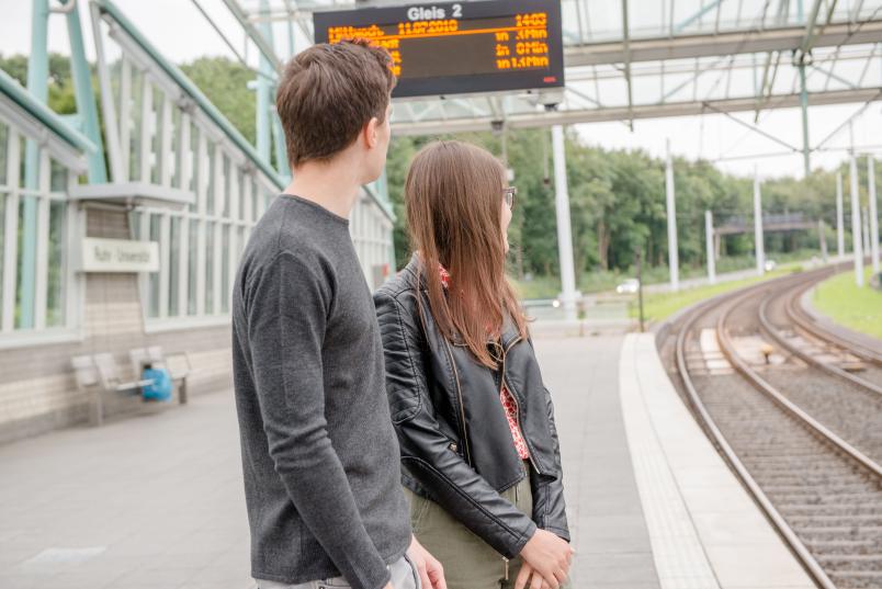 Studierende warten auf die Bahn.