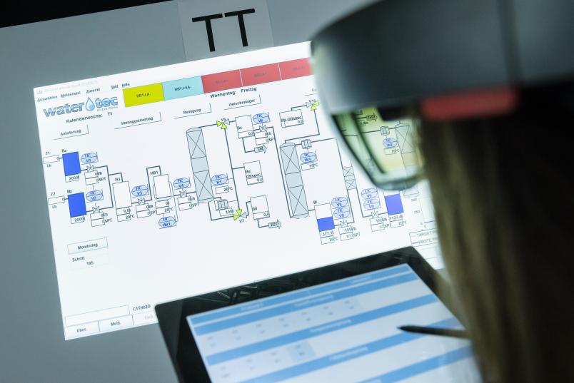 Eine Person mit Tablet vor der Projektion eines Schaltdiagramms