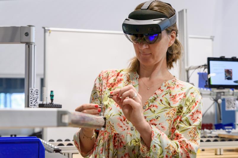 Eine Person mit Augmented-Reality-Brille setzt kleine Metallteile zusammen.