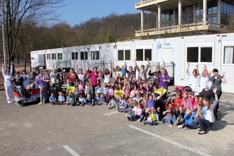 Wir ziehen um: Die Kinder und Mitarbeiterinnen der neuen Kita verlassen das Container-Provisorium auf dem GC-Parkplatz.