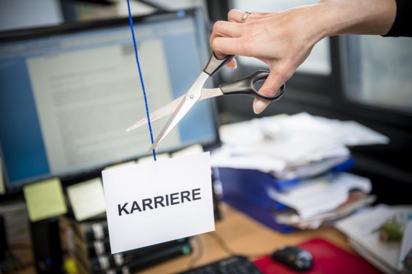 Mit einer Schere wird ein blaues Band zerschnitten. Am Ende des Bandes hängt ein Schild mit der Aufschrift Karriere.