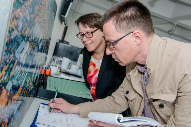 Rubens-Redakteur Arne Dessaul zeichnet symbolisch die Post ab. Kanzlerin Dr. Christina Reinhardt sieht ihm zu.