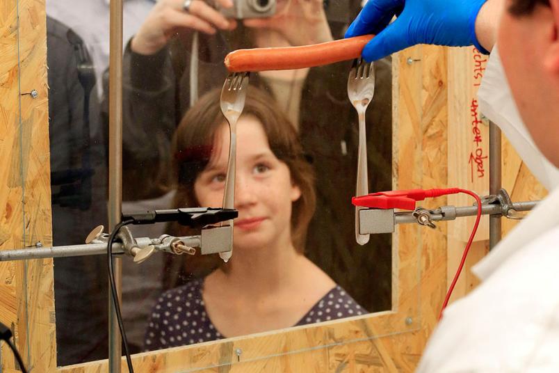 Wissenschaftler grillt mit Elektrizität ein Würstchen auf zwei Gabeln