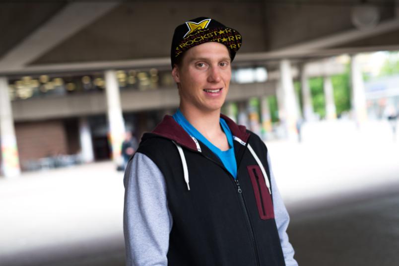 Junger Mann mit Baseballkappe steht vor einem Gebäude.