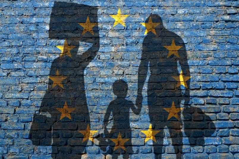 Flüchtlinge vor der Europaflagge.
