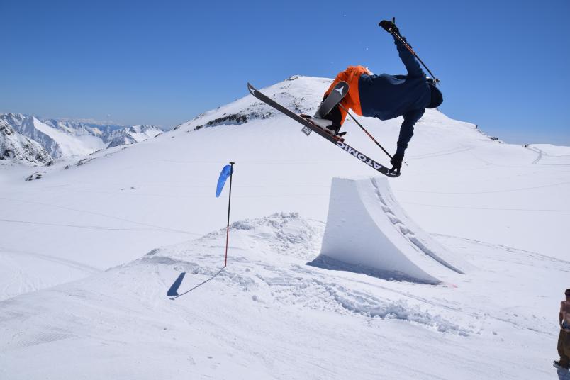 Skifahrer springt über einen Schneehügel und macht einen Trick in der Luft.