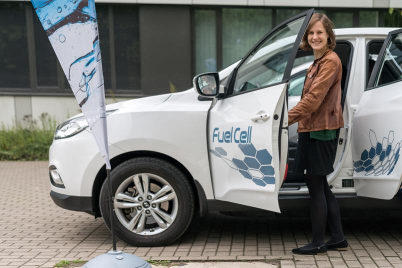 Junge Frau steigt in ein Brennstoffzellenauto ein.