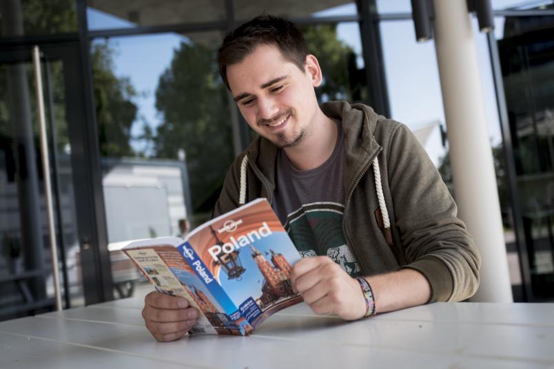 Student liest im Reiseführer über Polen.