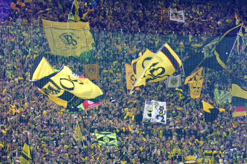 Fußball-Fans von Borussia-Dortmund schwenken Fahnen.