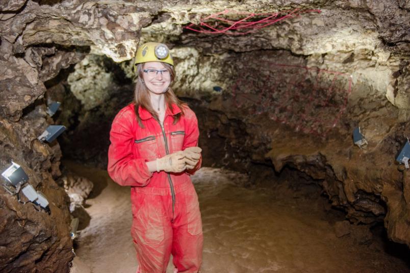 Studentin im roten Arbeitsanzug und gelben Helm in der Kluterthöhle. 