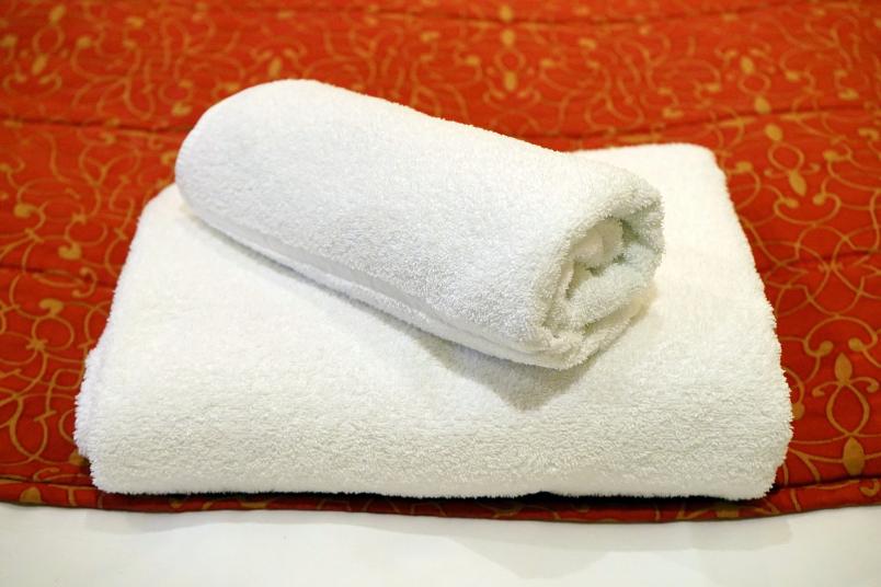 zwei weiße, auf einem Bett liegende Handtücher