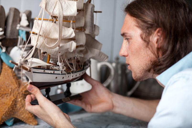 Junger Mann schaut Segelschiff an