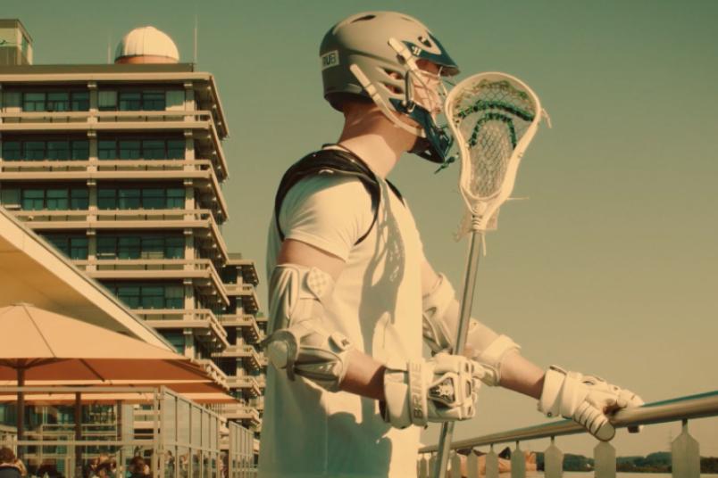 Lacrosse-Spieler auf der Mensaterrasse vor der Silhouette der Ruhr-Universität Bochum.