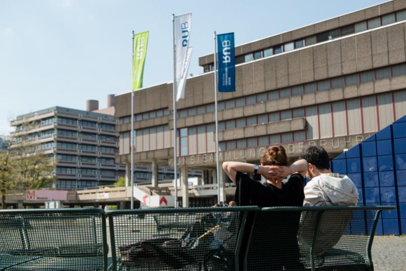 Studenten sitzen auf einer Bank vor der Kunstsammlung.