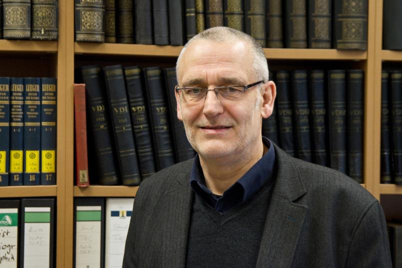 Mann mittleren Alters sitzt am Schreibtisch