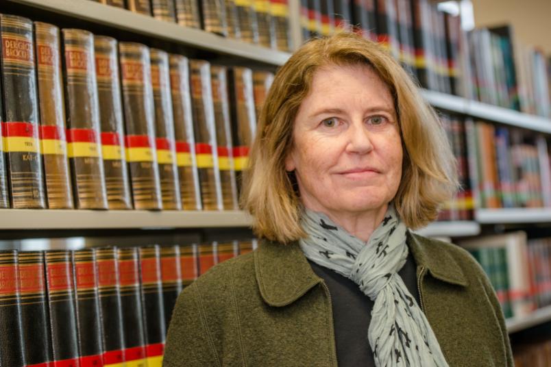 Porträt einer Frau, im Hintergrund Bücherregale