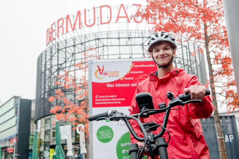Student mit Fahrradhelm präsentiert sein Lastenfahrrad.