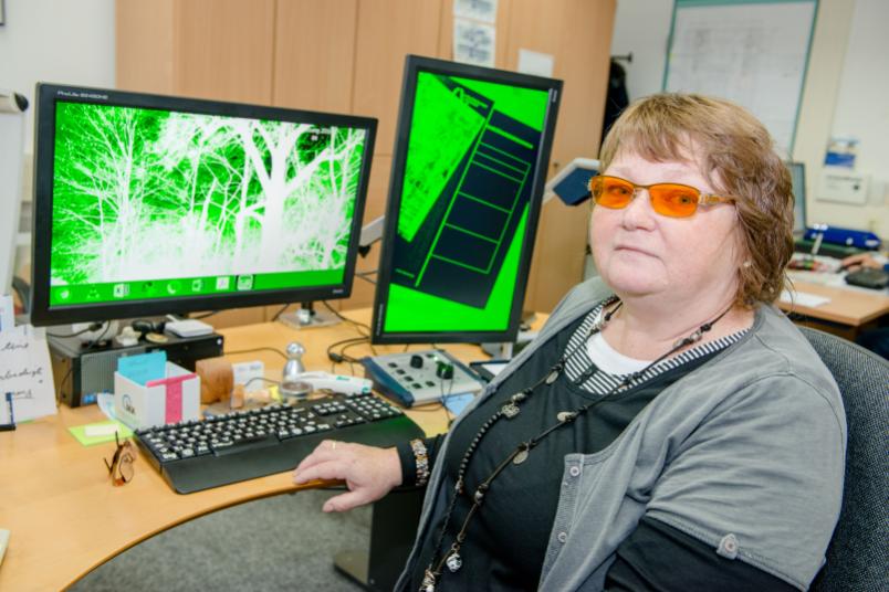 Frau sitzt an einem Schreibtisch mit einem grünen Computerbildschirm.