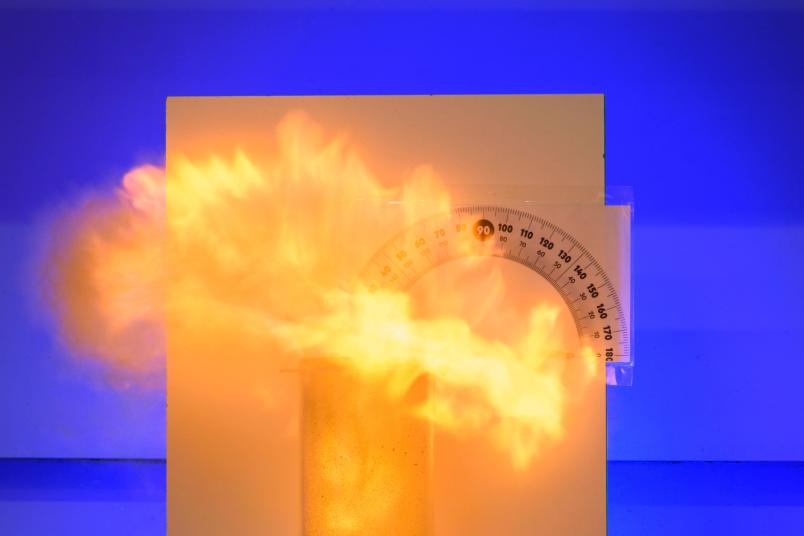 Feuer quillt aus einem Plexiglaszylinder.