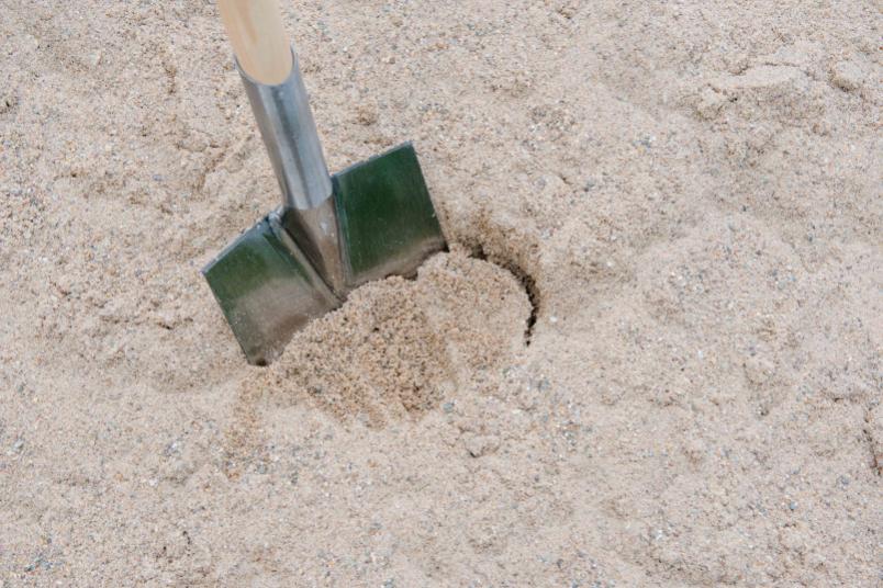 Spaten im Sand: ein Stellvertreterbild für den Spatenstich